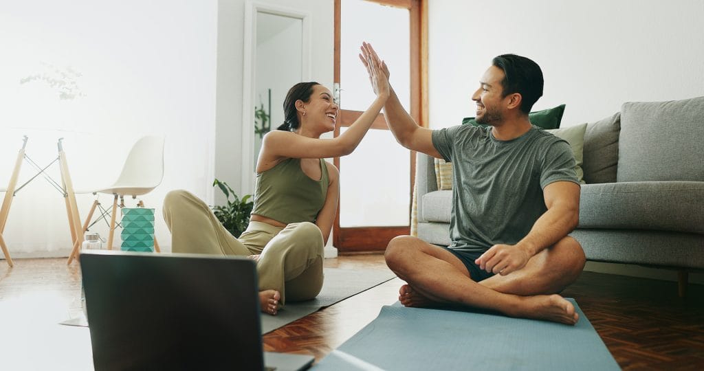 Man, woman and high five with laptop, exercise and warm up for online class and muscle training at home. Workout, internet video and couple with celebration, wellness and technology for health guide